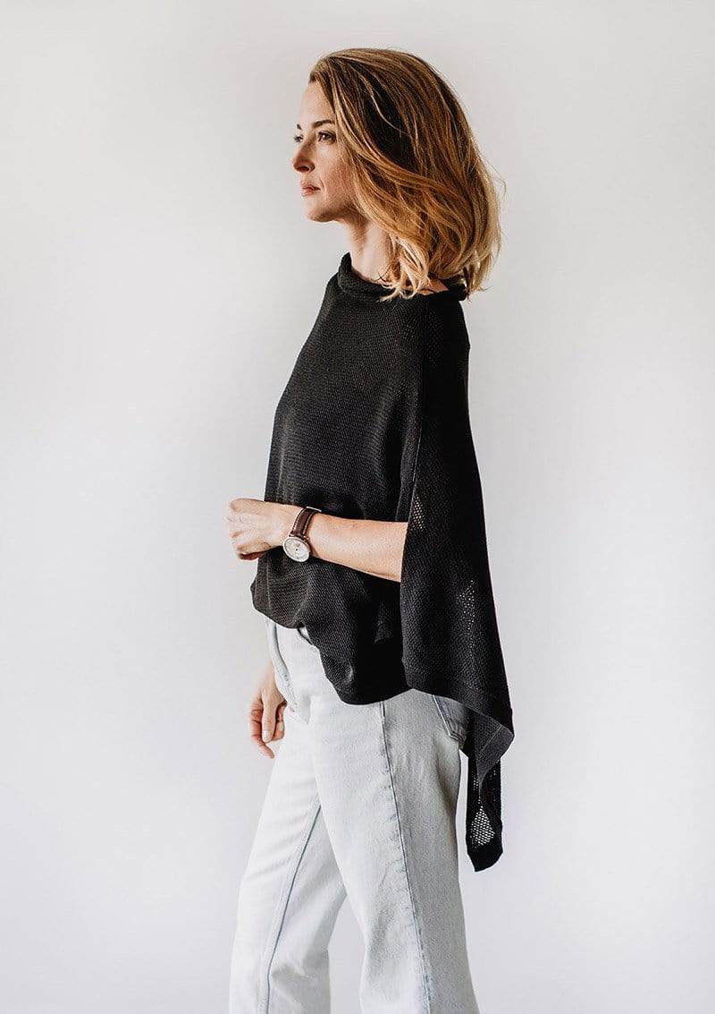 Side view of Emily Baldoni standing in a black knit Cocoon breastfeeding cover styled as a cape 