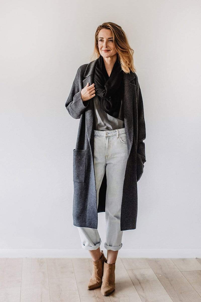 Emily Baldoni wearing grey jeans and long overcoat over black knit nursing cover styled as scarf