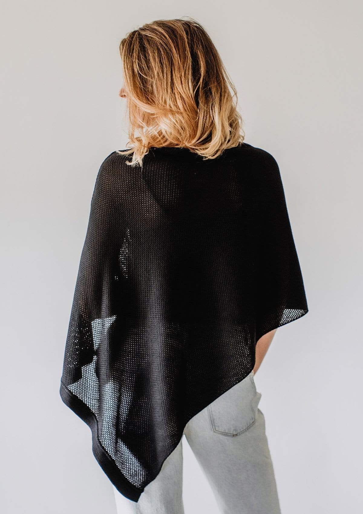 Back view of Emily Baldoni in sparkly black knit nursing poncho