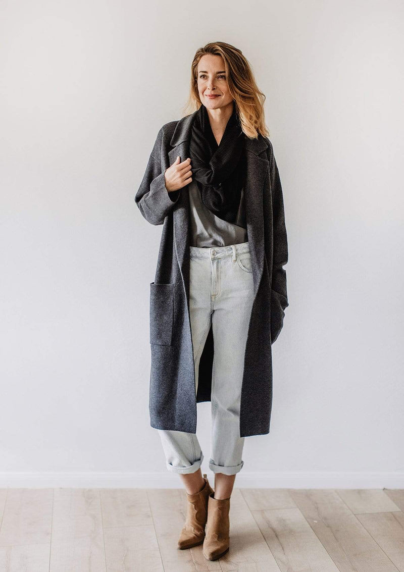 Emily Baldoni wearing grey jeans and long overcoat over black knit nursing cover styled as scarf