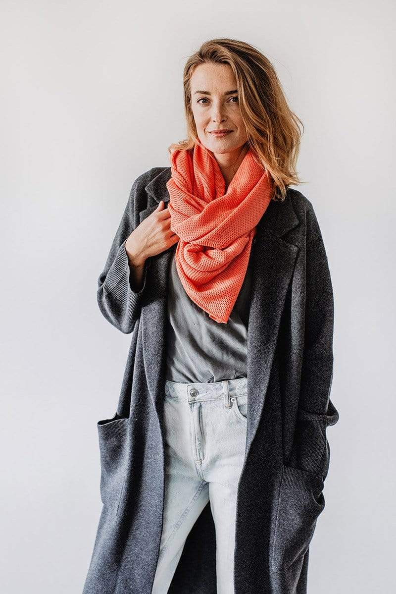 Emily Baldoni wearing overcoat and coral knit Cocoon nursing cover styled as scarf