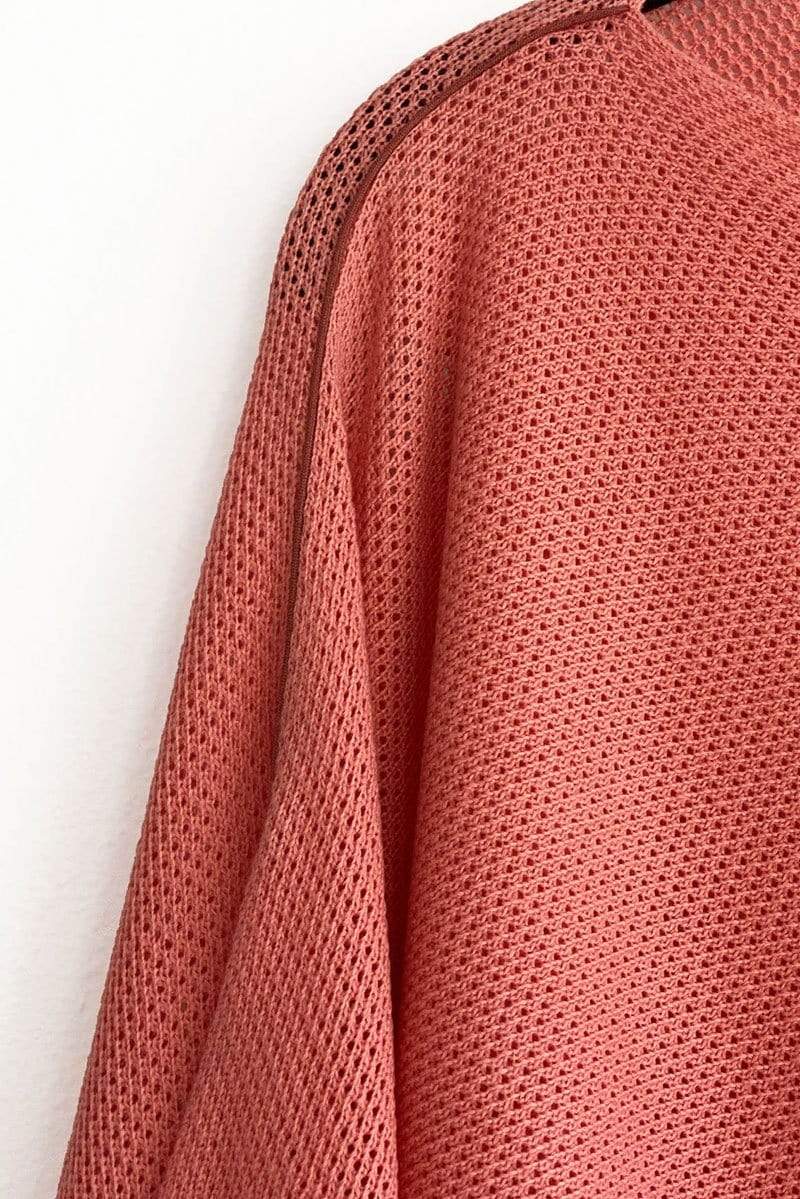 Closeup of coral breathable knit Cocoon nursing cover against white background